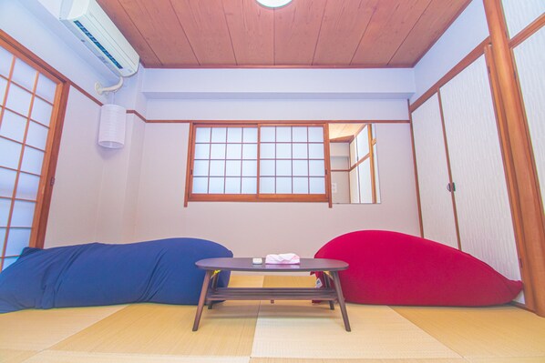 A traditional Japanese room with tatami flooring, a low table with cushions, and sliding doors.