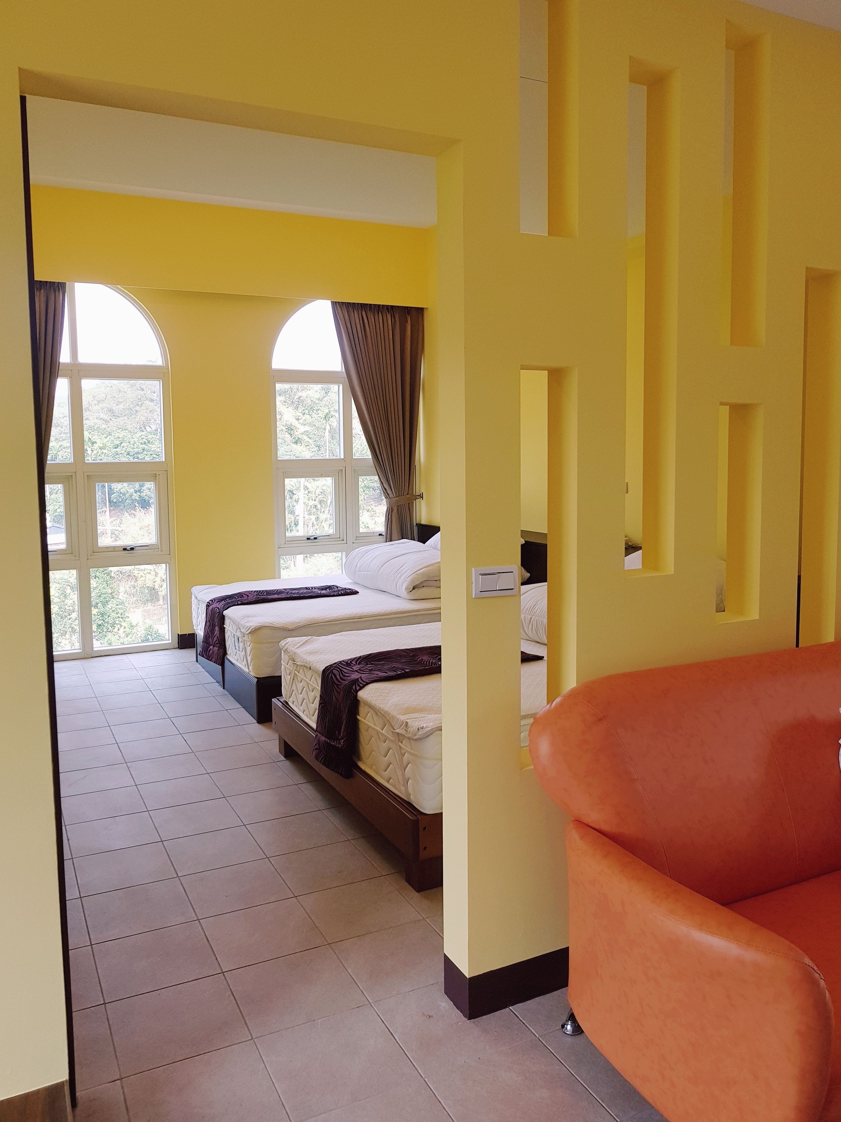 A hotel room with two beds, a large window, and a door leading to another room.
