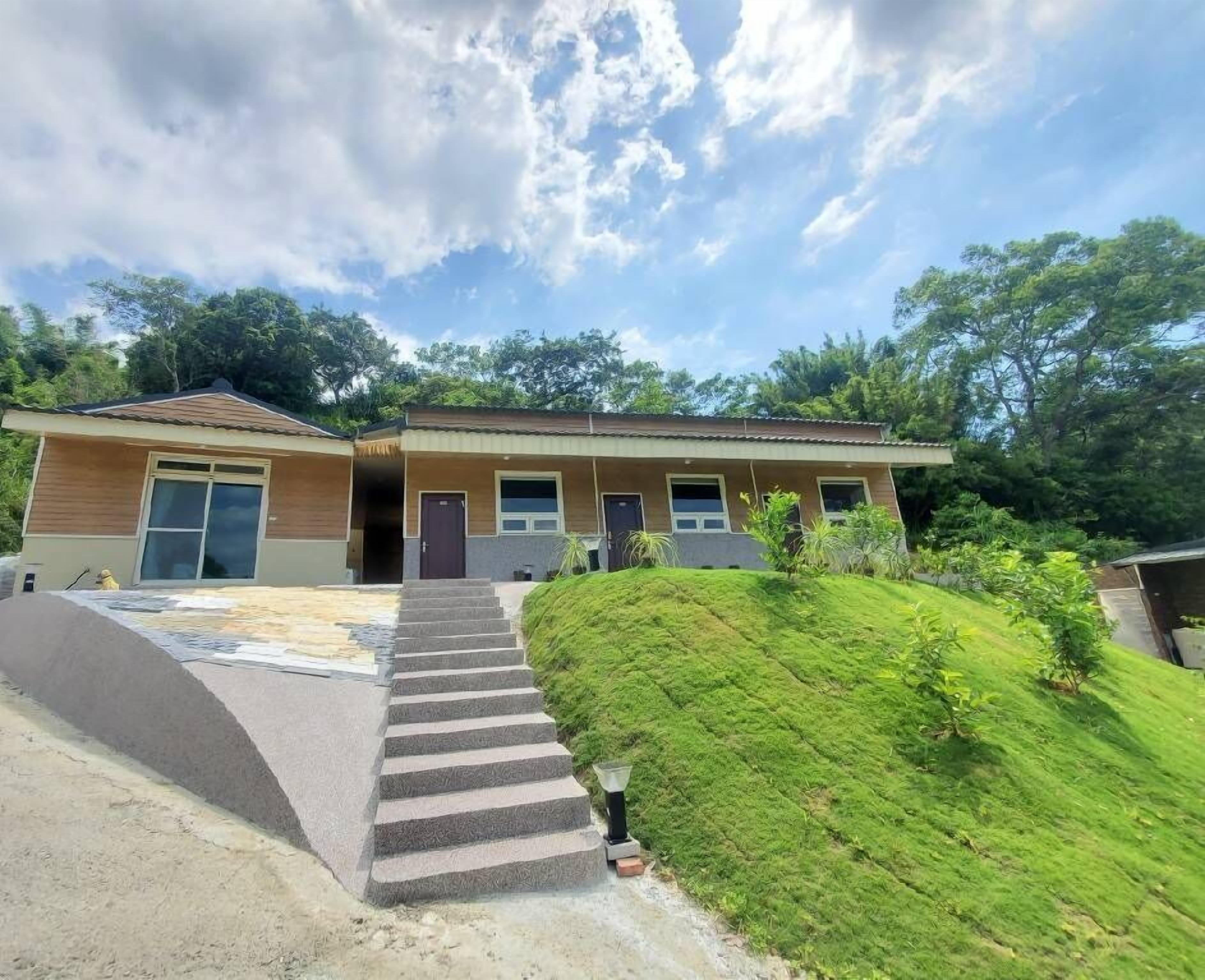 A two-story house with a front entrance, a driveway, and a small hill with grass.