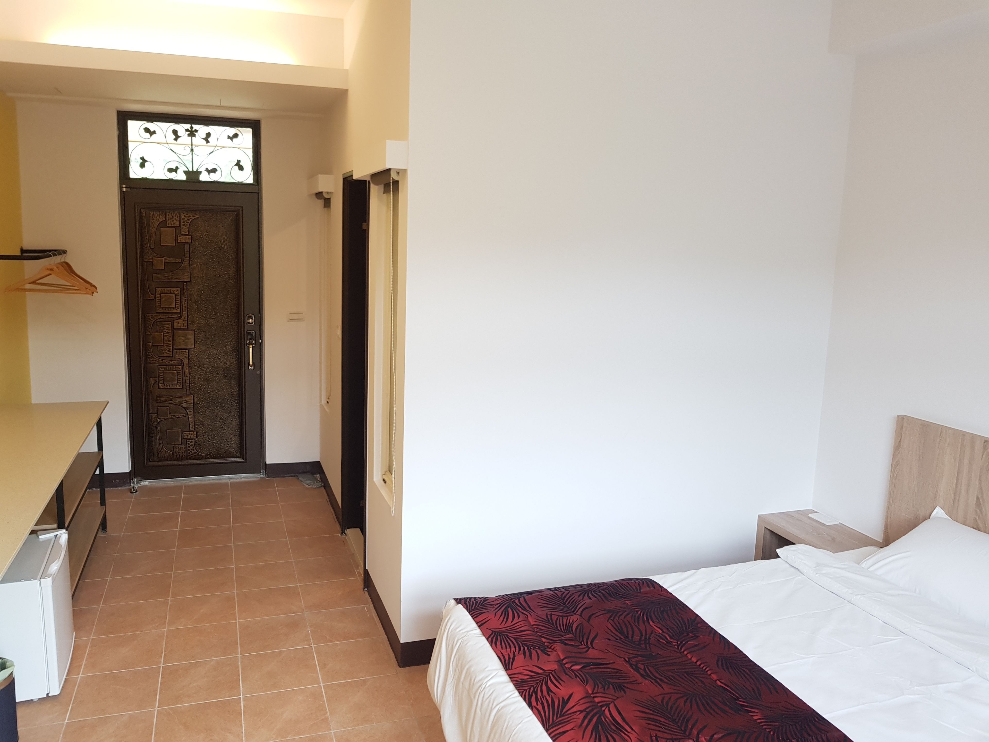 A hotel room with a bed, a nightstand, a desk, and a wardrobe.