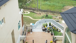 A residential building with a rooftop deck, a staircase, and a view of a forested area. - Moonshine B&B (Touwu)