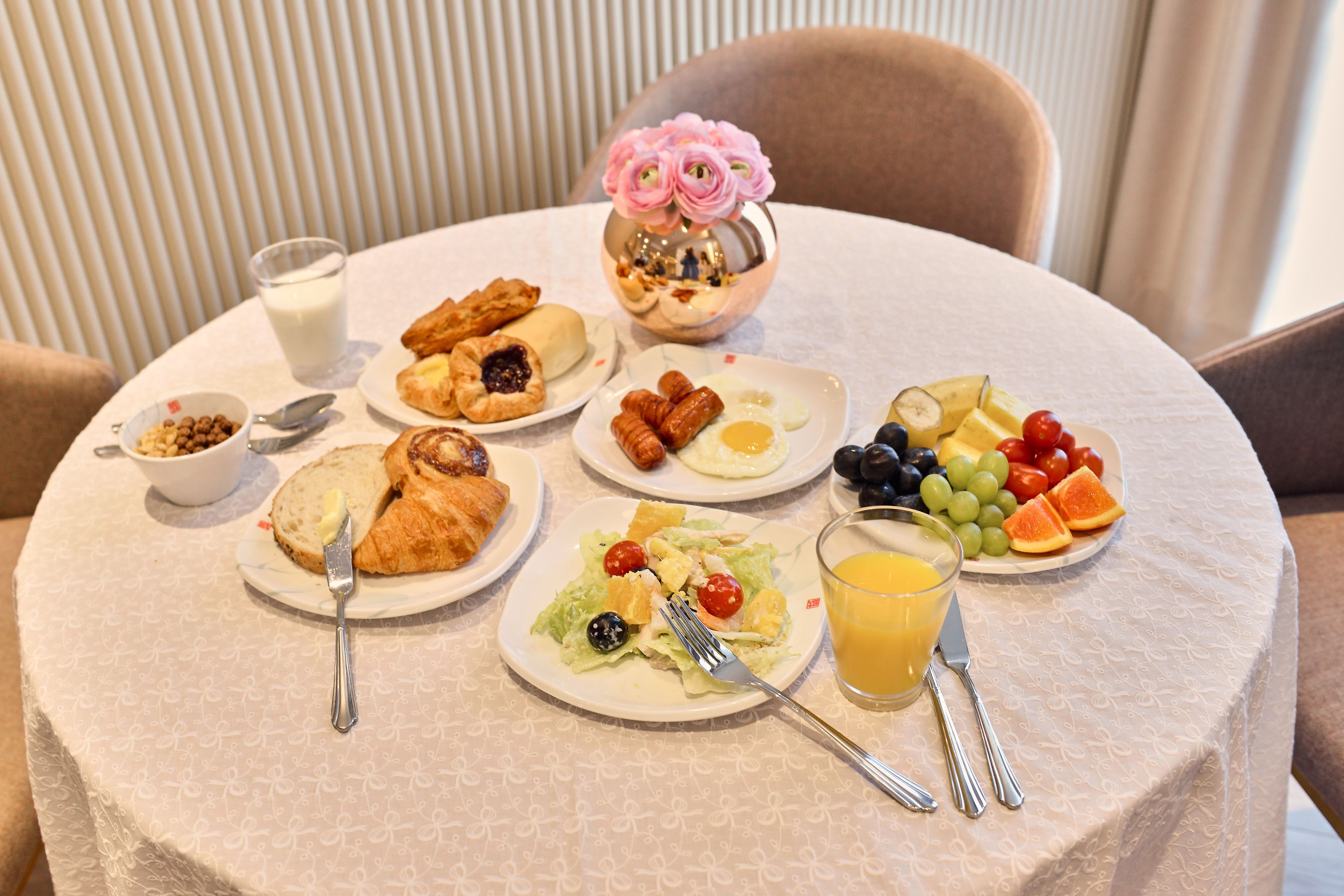 A breakfast table with various dishes including croissants, eggs, and fruits.