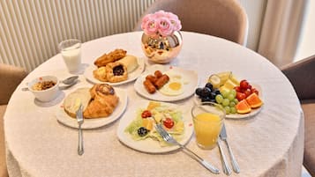 A breakfast table with various dishes including croissants, eggs, and fruits.