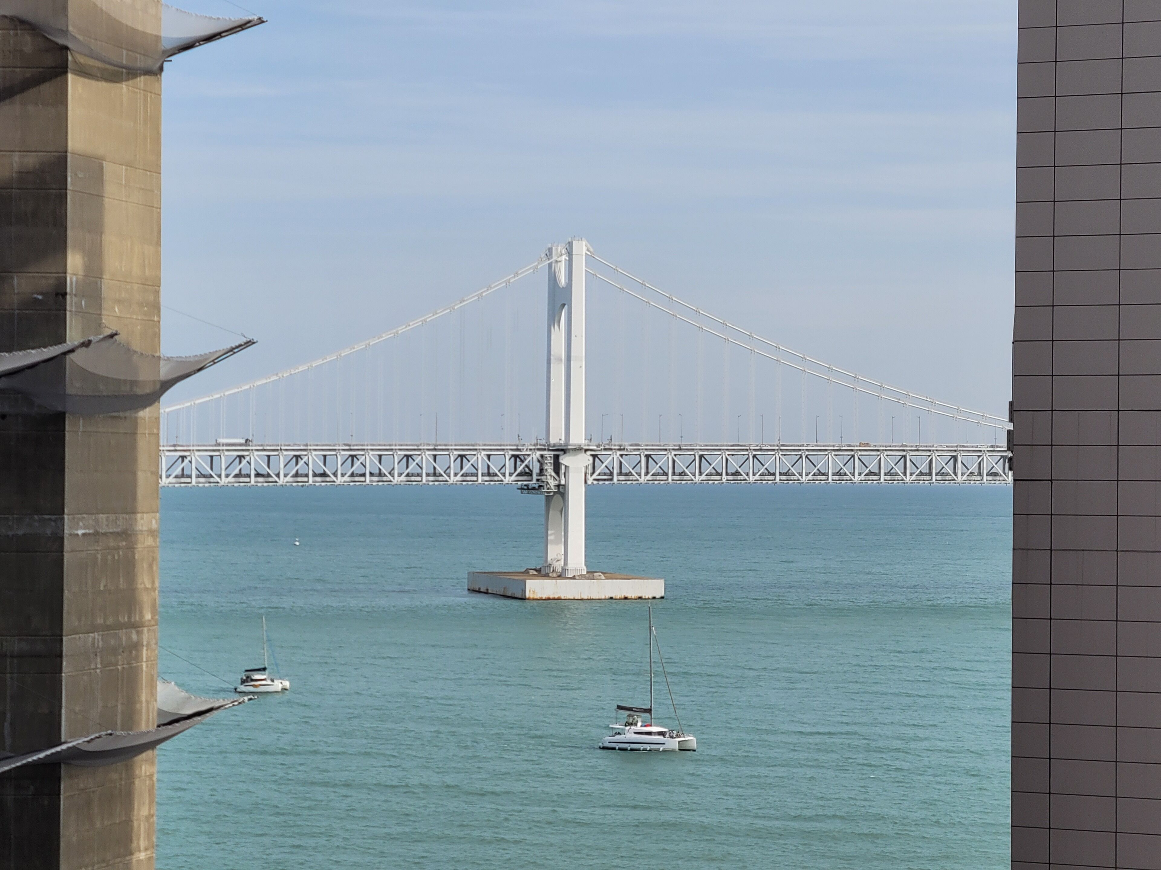 Un gran puente colgante sobre un cuerpo de agua, con barcos a la vista en primer plano.
