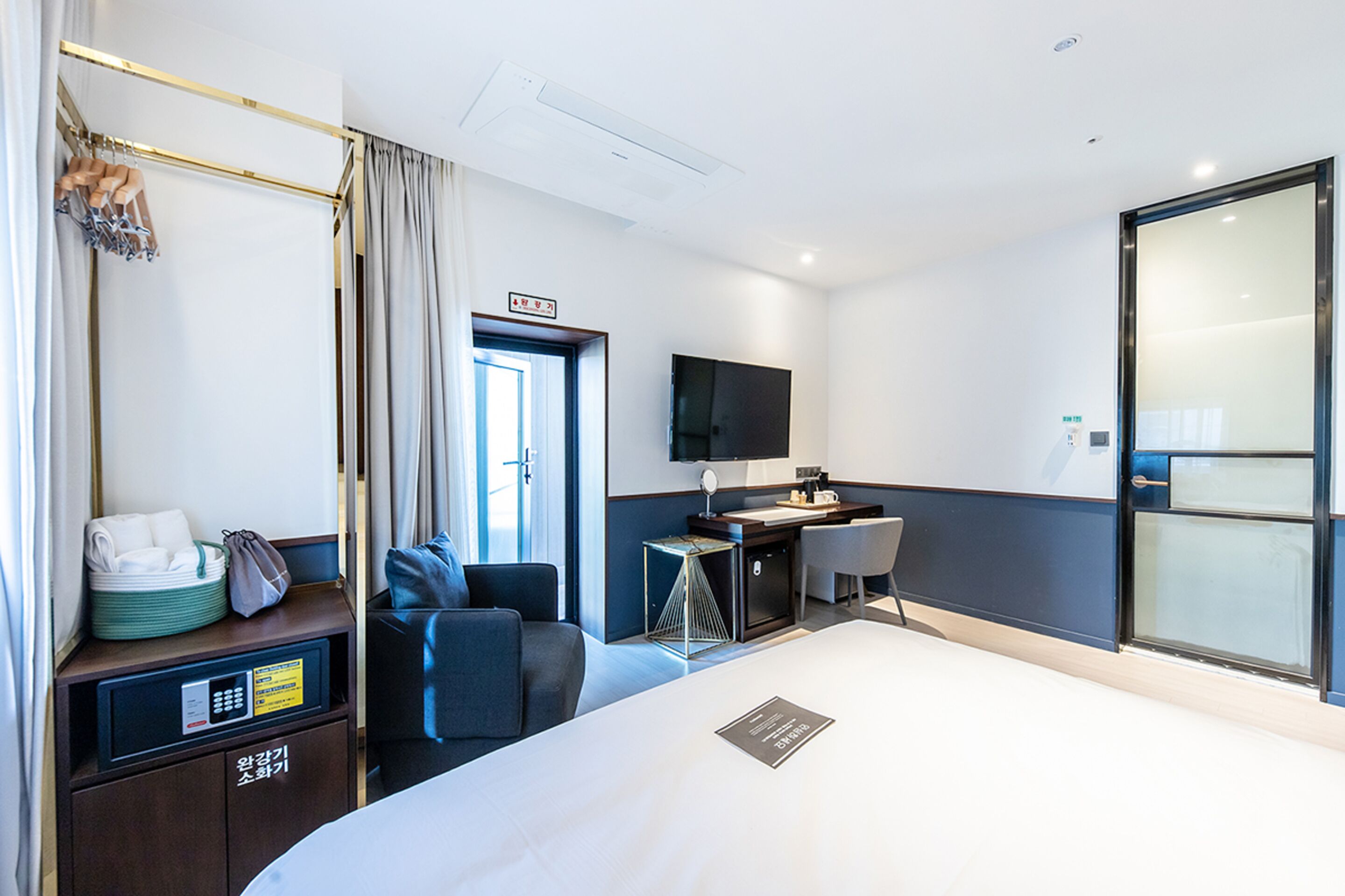 A hotel room with a bed, a desk, a chair, a TV, and a minibar.