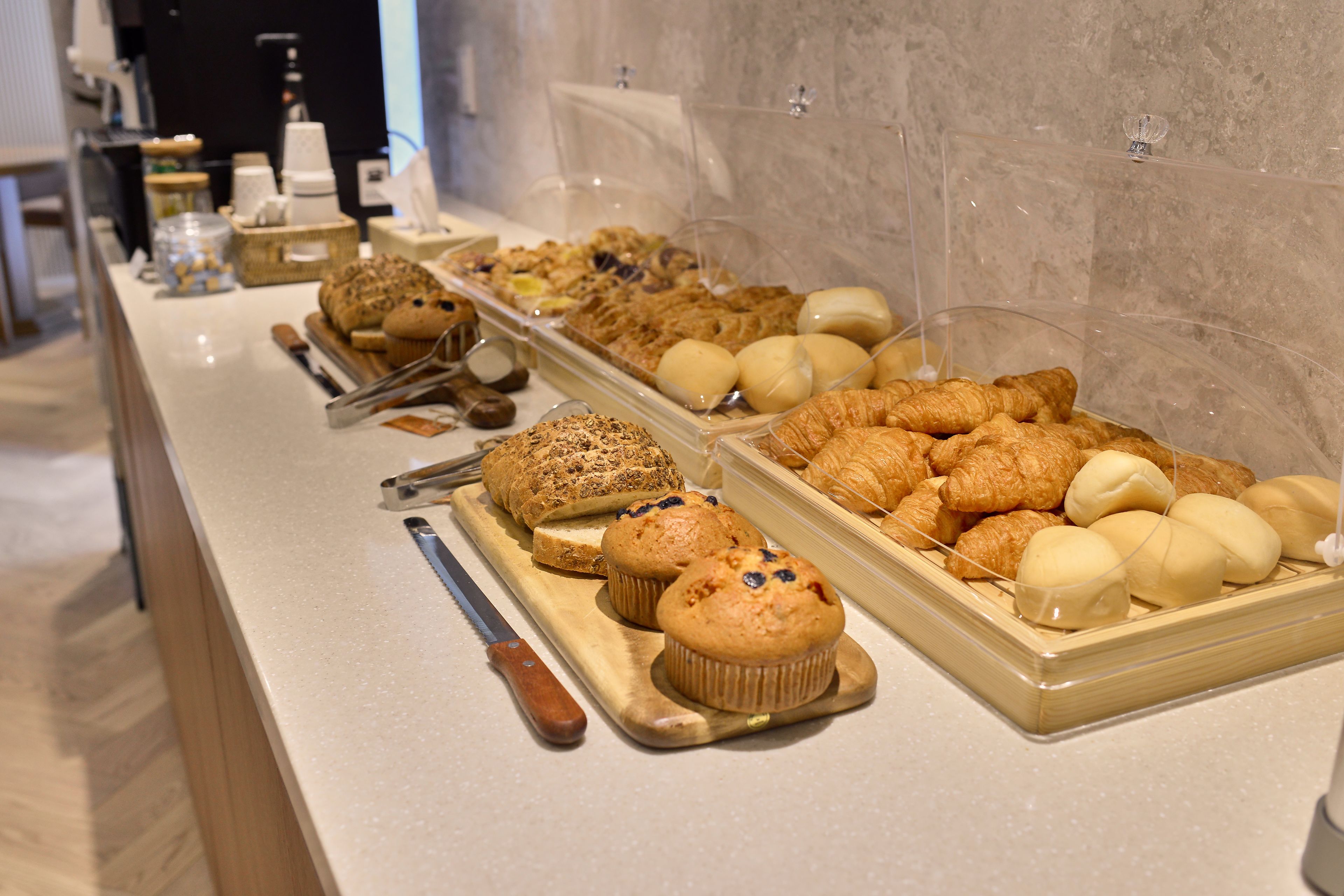 A buffet with various baked goods including muffins, croissants, and bread.