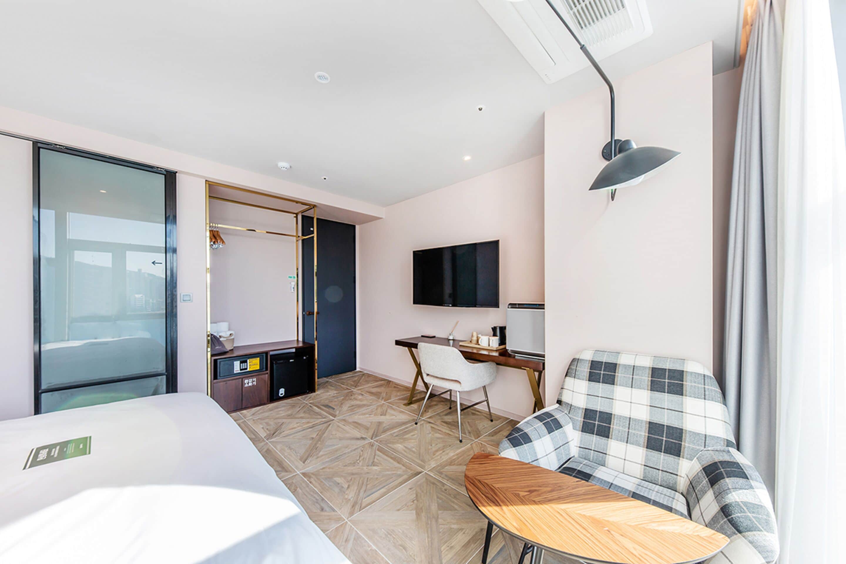 Een moderne hotelkamer met een bed, een bureau, een stoel, een televisie en een groot raam.