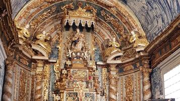 An ornate church interior with a high ceiling, detailed frescoes, and a central altar.