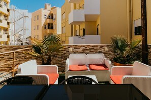 A terrace with wicker furniture, potted plants, and a stone wall.