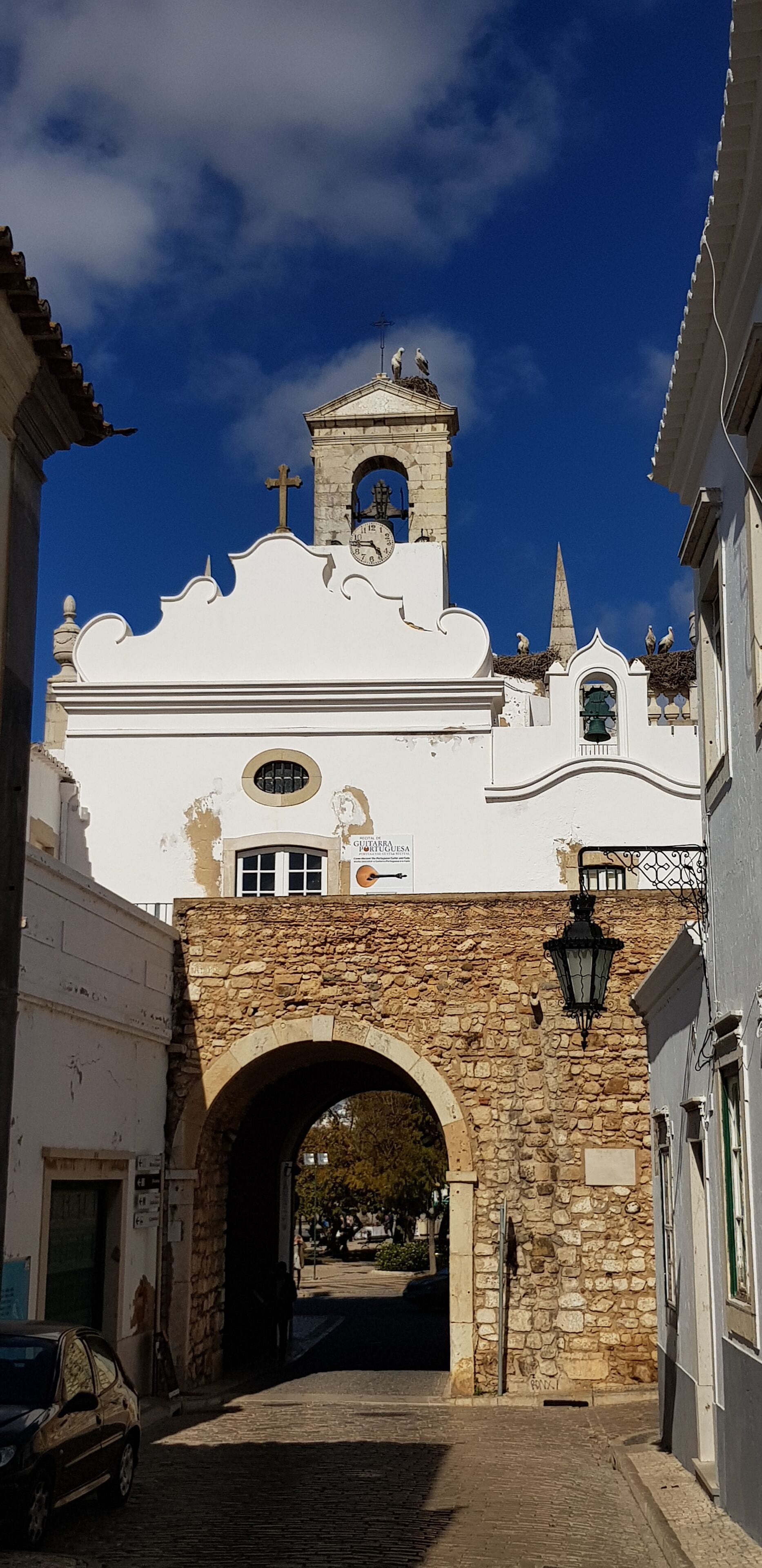 A historic building with a clock tower, stone archway, and a bell.