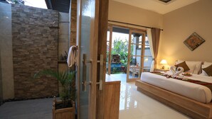 A bedroom with a large bed, a wooden bench, a shower area, and a view of the outdoors. - Uma Dhari Villa (Sukawati)