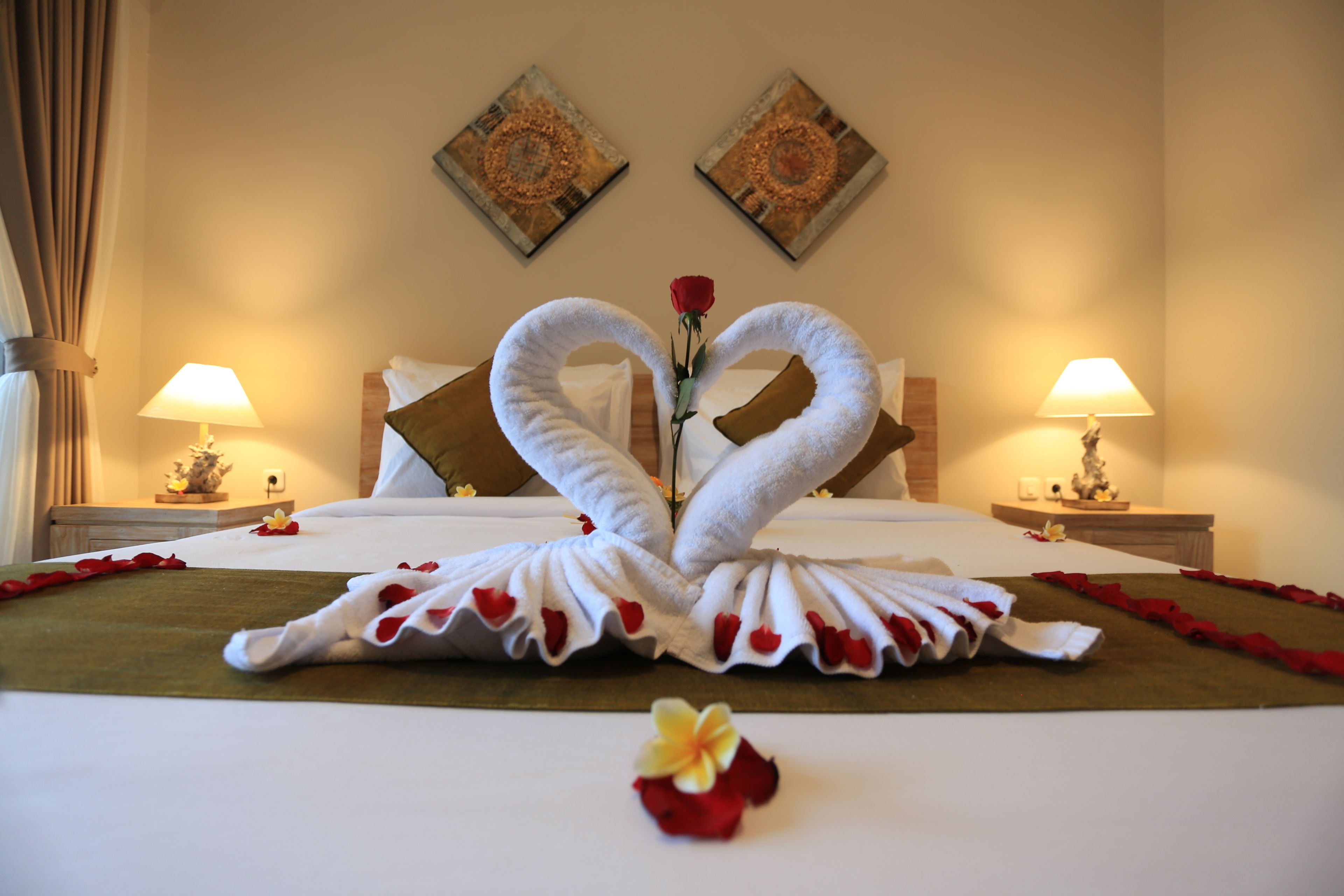 Een hotelkamer met een bed, twee wandlampen en twee decoratieve kunstwerken.
