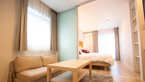 A modern hotel room with a sofa, a small table, a bed, and a wardrobe. - Apartment Hotel Tenjin Tumugu (Fukuoka)