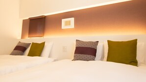 A hotel room with a neatly made bed, a headboard with built-in lighting, and a wall-mounted light fixture. - Apartment Hotel Tenjin Tumugu (Fukuoka)