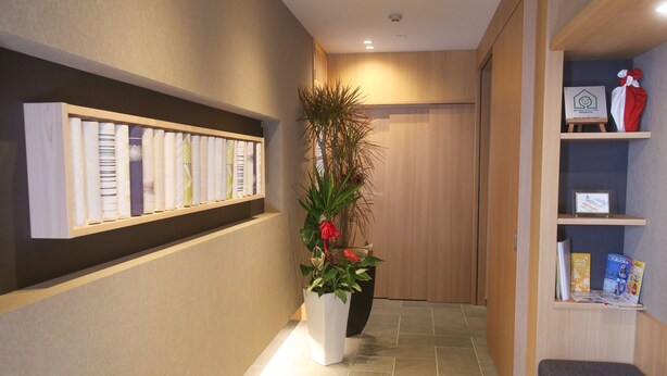 A hallway with a reception desk, a plant, and a display of brochures. - Apartment Hotel Tenjin Tumugu (Fukuoka)