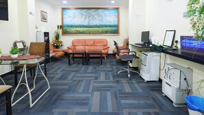 A reception area with a couch, chairs, a desk, a computer, and a clock on the wall. - Hotel Sunjoy9 OKR Near Midvalley 10 Mins Only (Kuala Lumpur)