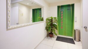 A hotel lobby with a green elevator, a potted plant, and a trash bin. - Hotel Sunjoy9 OKR Near Midvalley 10 Mins Only (Kuala Lumpur)