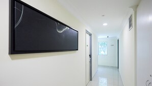 A hallway with a large black artwork on the left, a door on the right, and a window at the end. - Hotel Sunjoy9 OKR Near Midvalley 10 Mins Only (Kuala Lumpur)