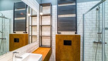 A modern bathroom with a glass shower enclosure, a white sink, and a wooden vanity.