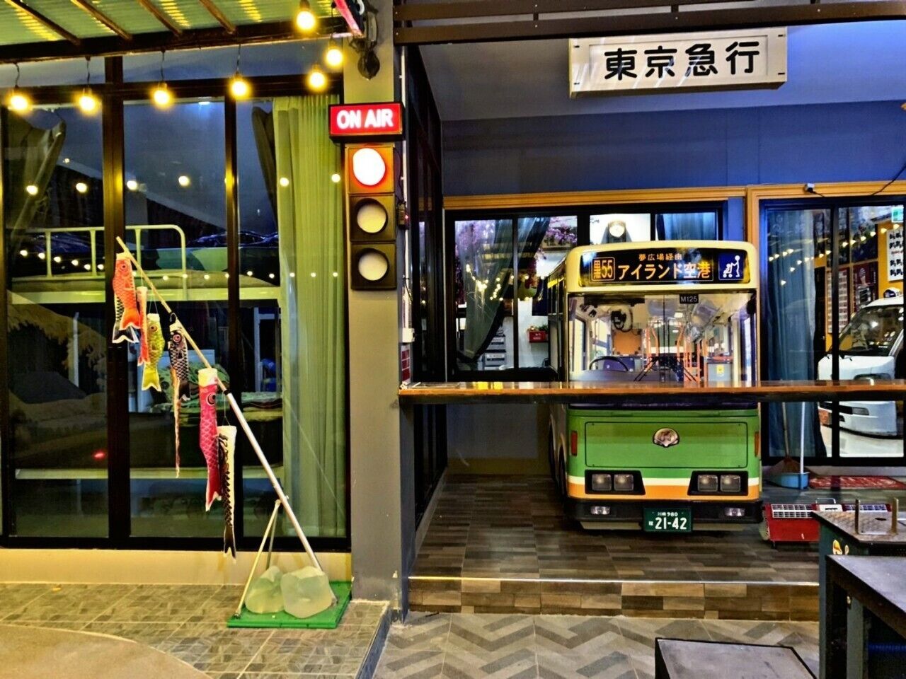 A bus parked inside a building with a sign reading "ON AIR" and a bus number "55" visible through the window.