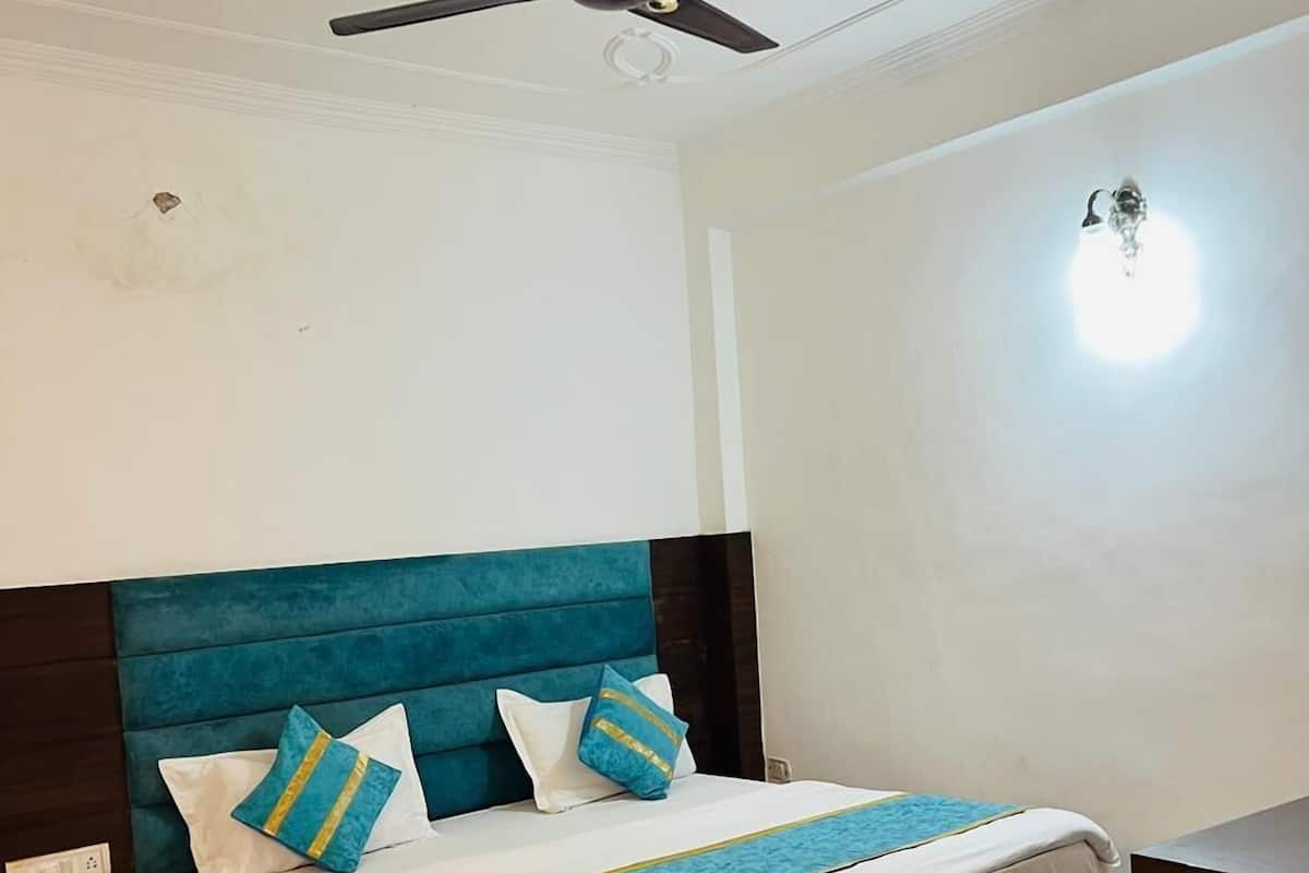 A bedroom with a bed, a nightstand, a ceiling fan, and a wall-mounted light fixture.