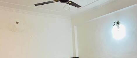Un dormitorio con cama, mesita de noche, ventilador de techo e iluminación empotrada en la pared.