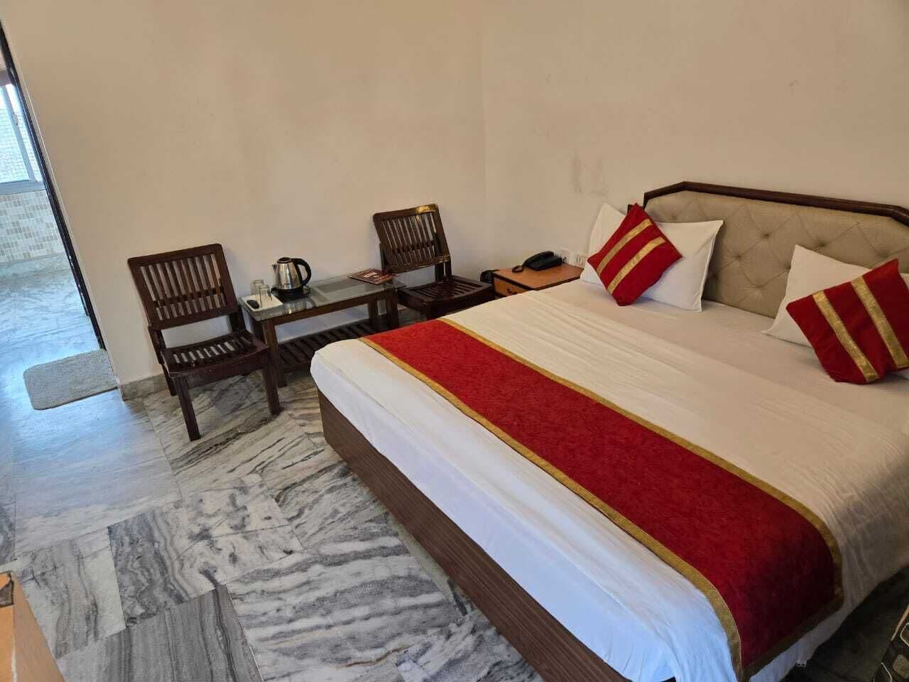 A hotel room with a bed, two chairs, a small table, and a telephone.