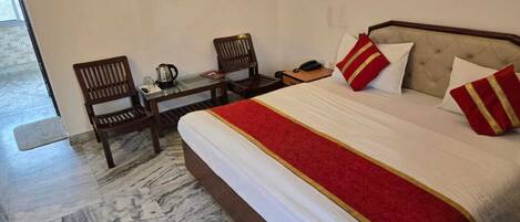 A hotel room with a bed, two chairs, a small table, and a telephone.