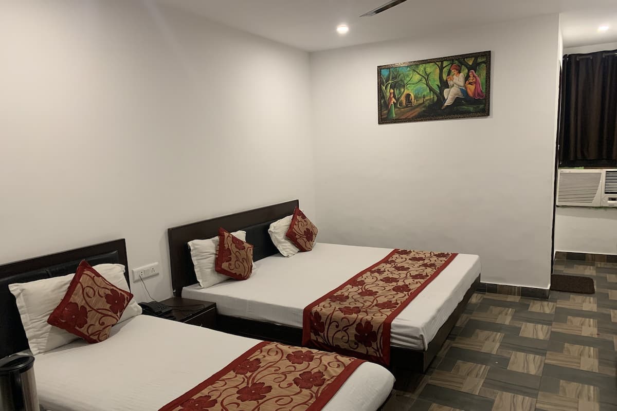 A hotel room with two beds, a painting on the wall, and a tiled floor.