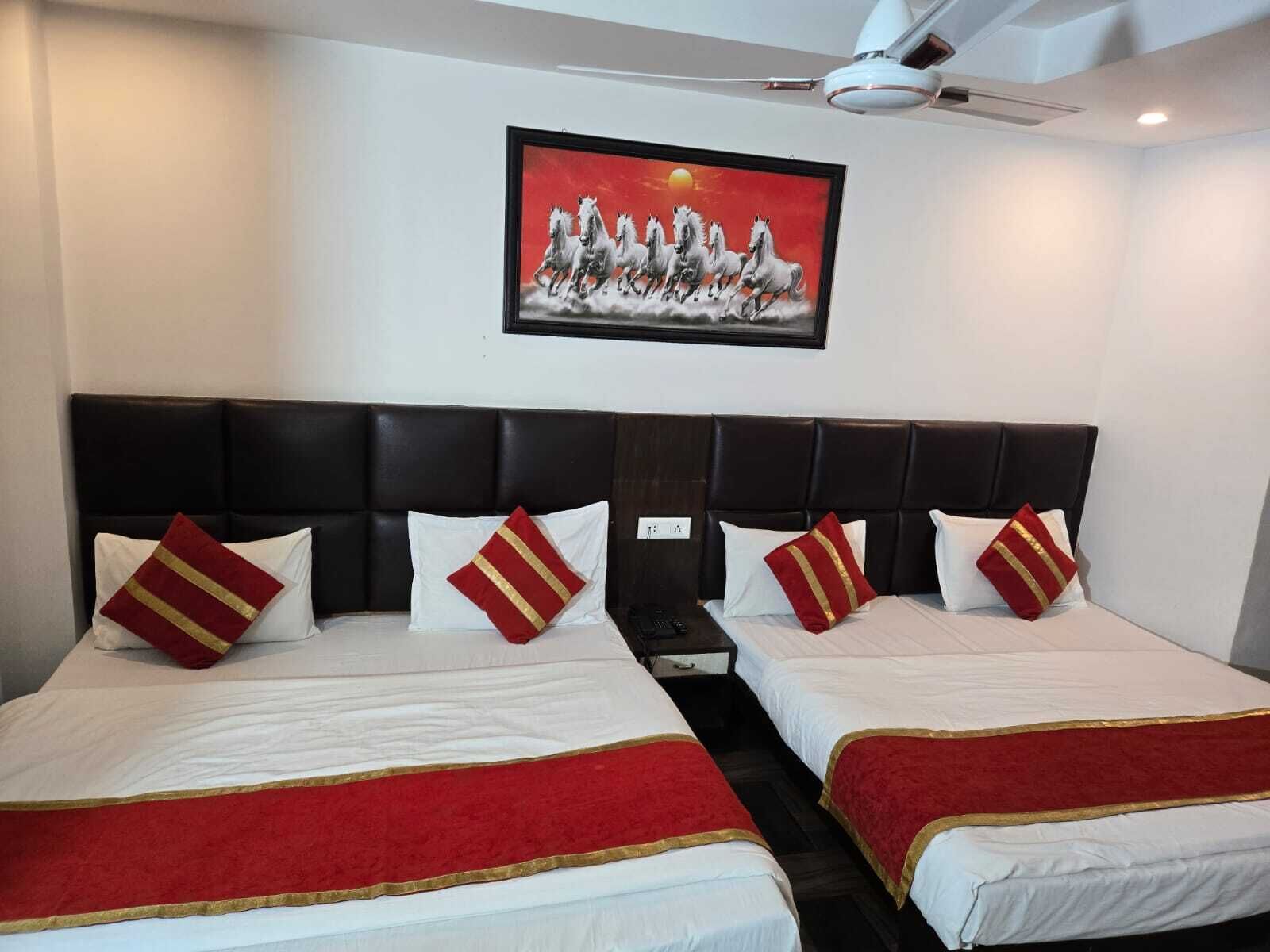 A hotel room with a large bed, two bedside tables, a ceiling fan, and a framed painting on the wall.