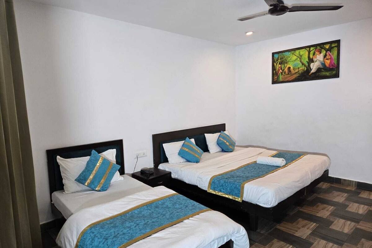 A hotel room with two beds, a ceiling fan, and a painting on the wall.