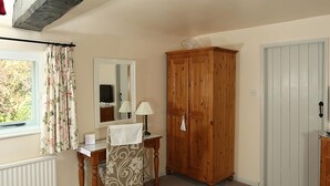 A room with a wooden cabinet, a desk with a mirror, a chair, and a radiator. - The Barns Country Guesthouse (Retford)
