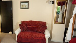 A room with a white sofa covered in a red patterned blanket, a framed picture on the wall, and a mirror with a gold frame. - The Barns Country Guesthouse (Retford)