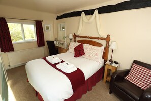 A neatly made bed with a red and white bedspread, a wooden headboard, and a bedside table with a lamp and a phone. - The Barns Country Guesthouse (Retford)