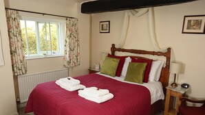 A neatly made bed with a red bedspread, two pillows, and two folded white towels. - The Barns Country Guesthouse (Retford)