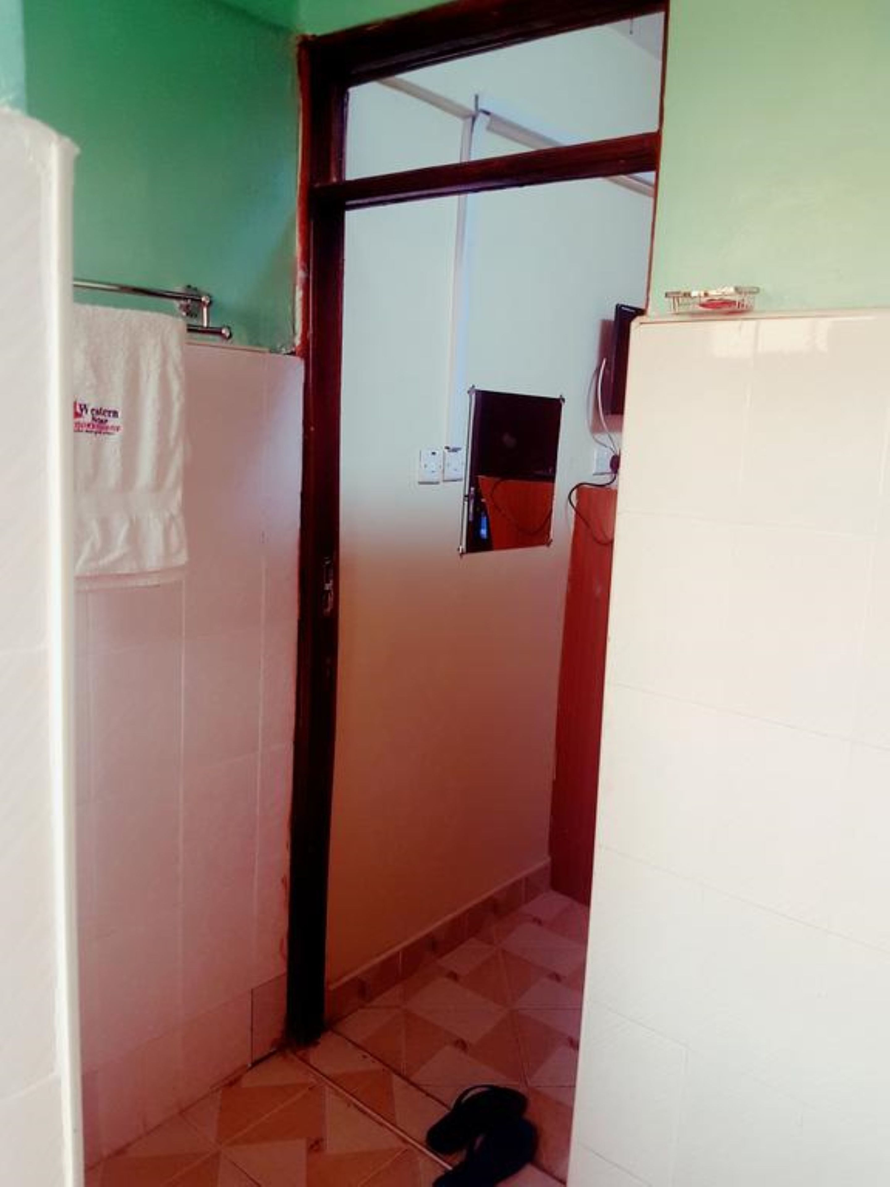 A narrow hallway with a tiled floor, a white door, and a small window.