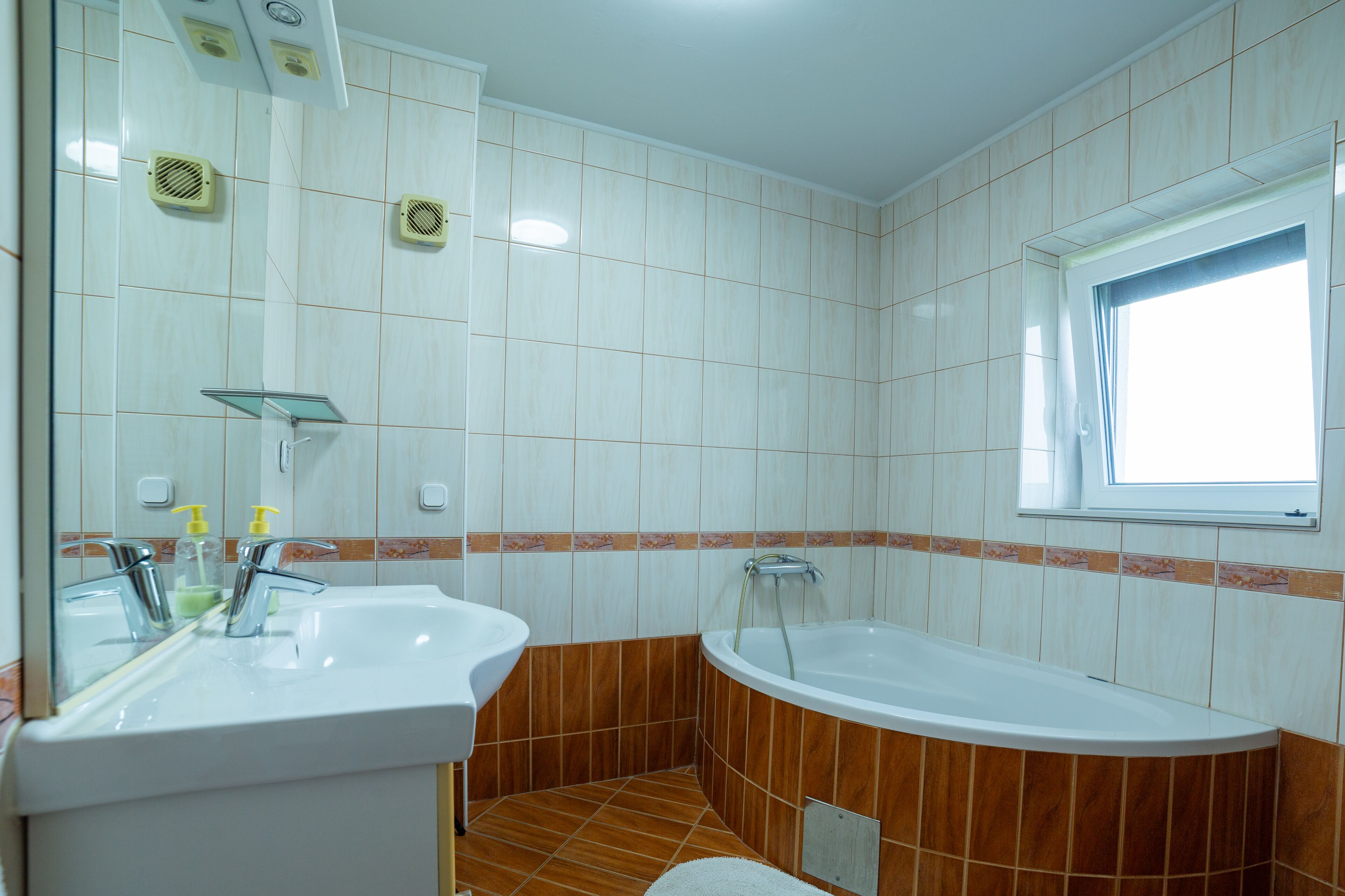 Une salle de bain avec deux lavabos, une baignoire et une fenêtre.