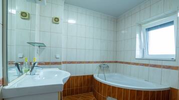 Une salle de bain avec deux lavabos, une baignoire et une fenêtre.