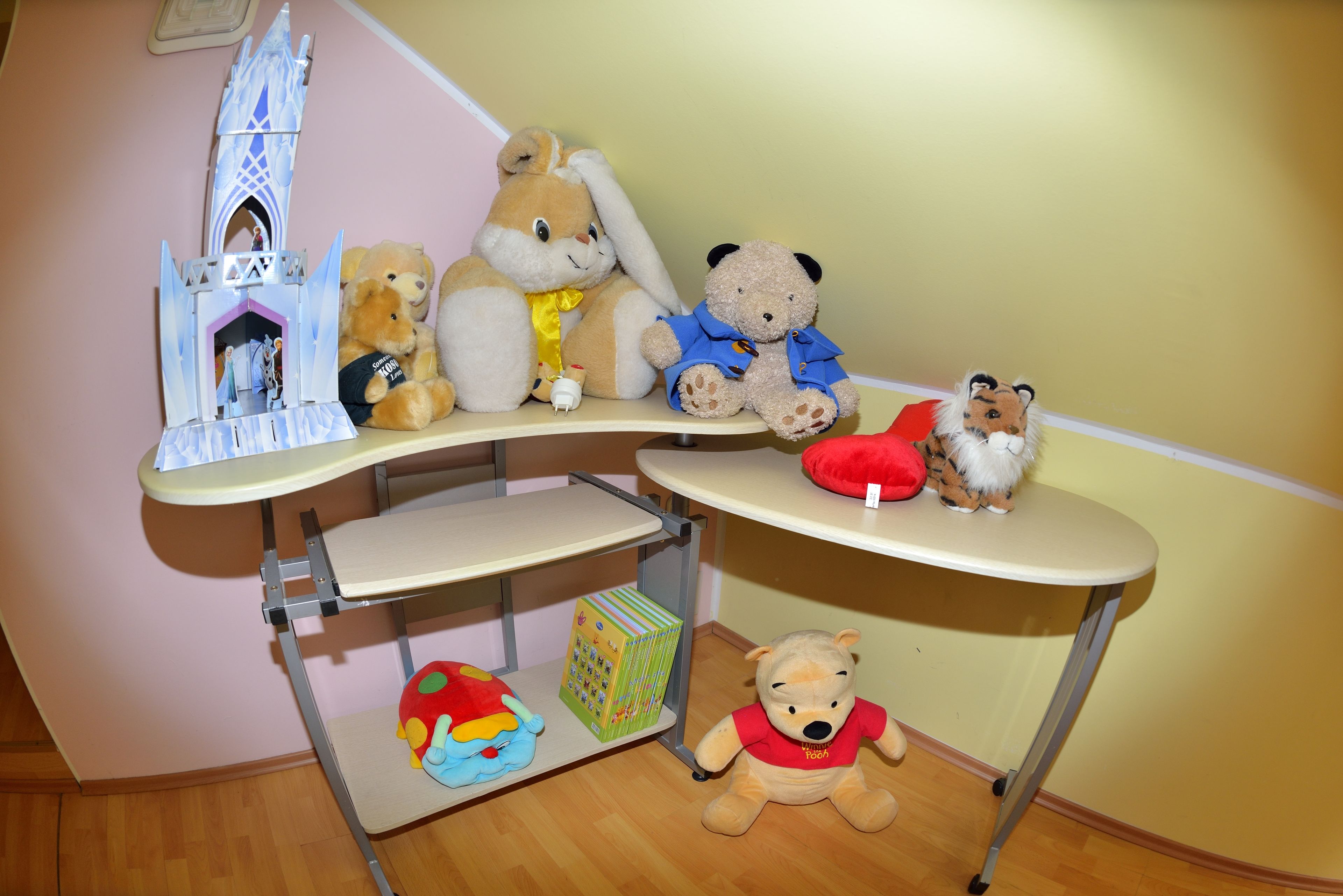 Een kamer met een kleine tafel waarop diverse knuffeldieren en een speelgoedkasteel staan.