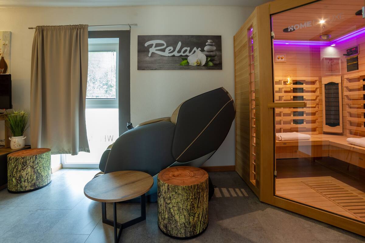 A modern room with a relaxation chair, a small table, and a wooden cabinet.