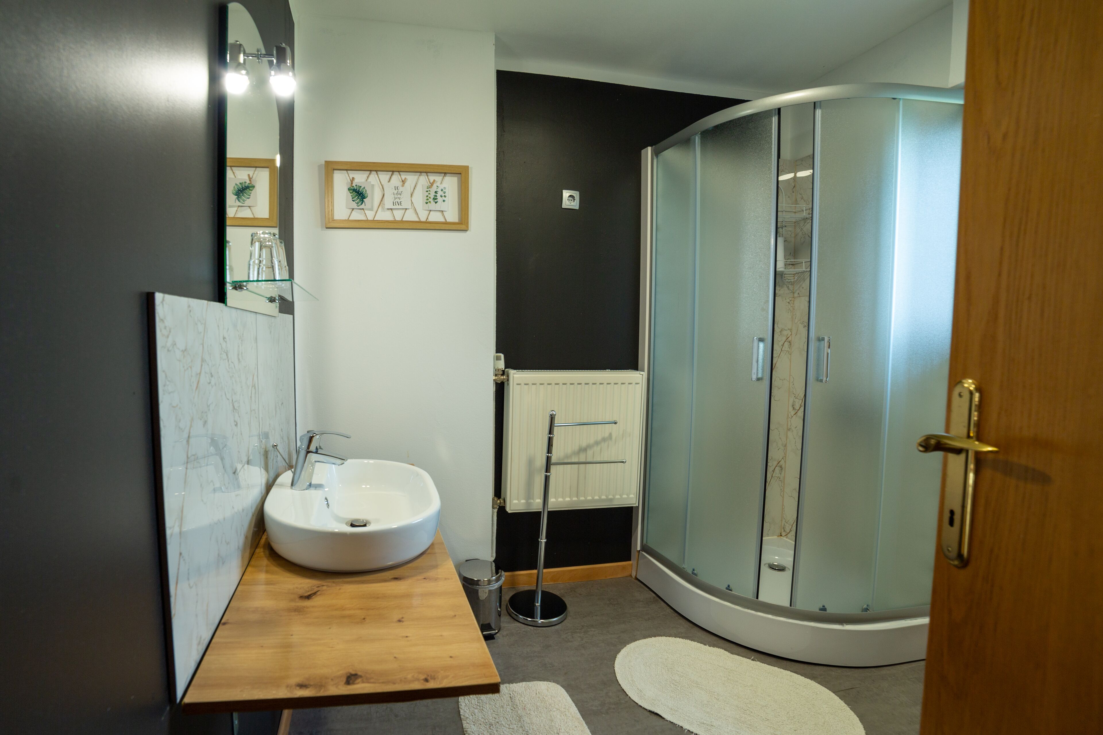 Ein modernes Badezimmer mit einem weißen Waschbecken, einer Holzauskleidung und einer Duschkabine aus Glas.