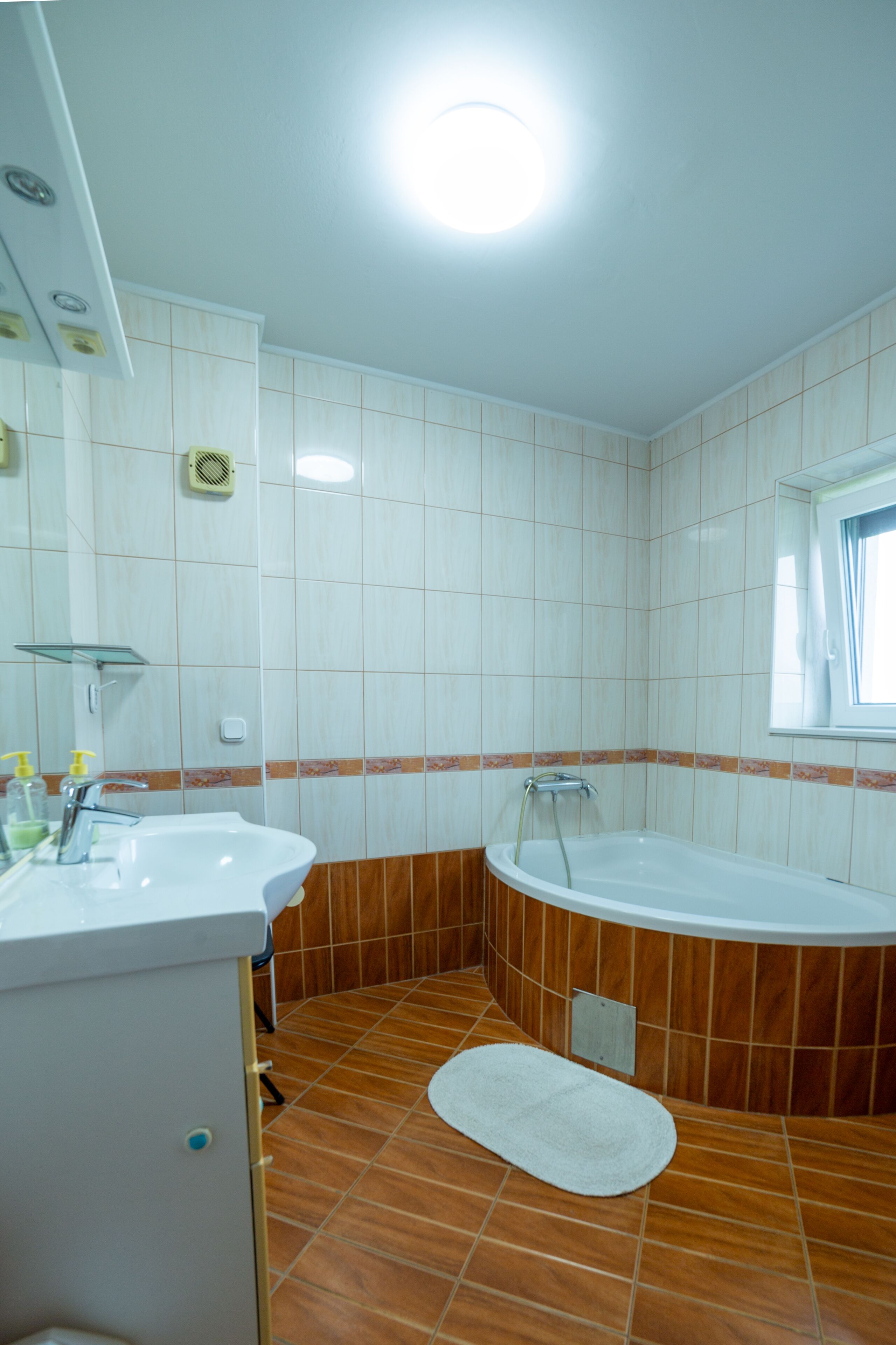 A bathroom with a sink, mirror, and bathtub.