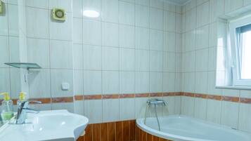 A bathroom with a sink, mirror, and bathtub.