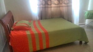 Ein Einzelbett mit einer grün-rot gestreiften Tagesdecke in einem Raum mit einem hölzernen Kopfteil.