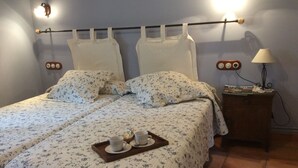 A double bed with floral bedding, a tray with cups and a teapot, and a nightstand with a lamp. - Casa Rural l'Era de Ferro (La Vall de Boi)