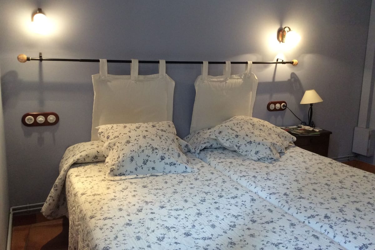 A bed with floral bedding, a headboard with a light fixture, and bedside lamps.