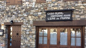 A rustic stone building with a sign indicating it offers rural accommodations and rooms. - Casa Rural l'Era de Ferro (La Vall de Boi)