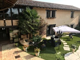 Un patio de hotel con una palmera, asientos al aire libre y una sombrilla blanca.