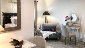 Un dormitorio con cama, escritorio, silla, espejo, lámpara y televisor.
