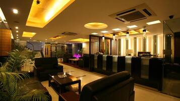 A modern hotel lobby with leather seating, a reception desk, and ambient lighting.